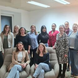 Zu sehen sind Frauen des Netzwerks in einem Raum stehend und auf zwei Sesseln sitzend